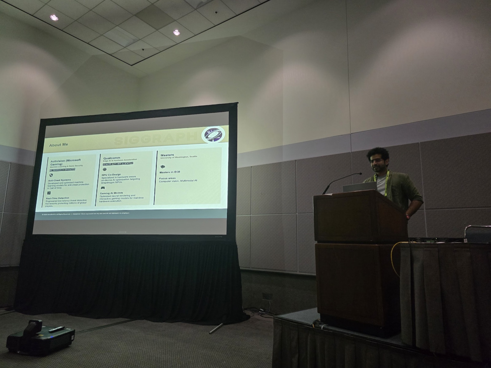 Mathew Varghese presenting the AI Level of Detail talk at a podium beside a projected SIGGRAPH slide